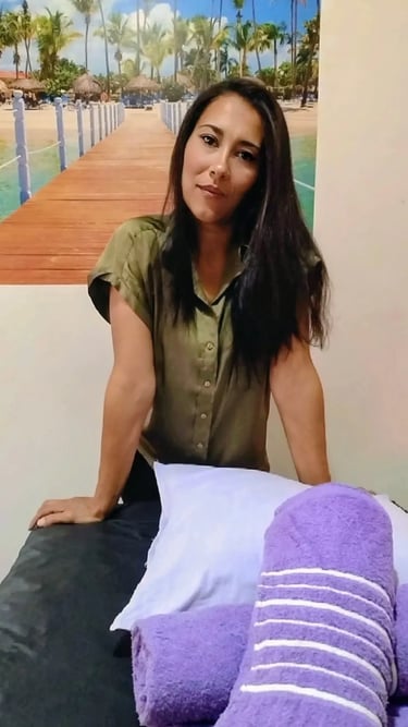 Masajista Lorena con blusa verde junto a la camilla y toallas moradas en su gabinete de Congreso.