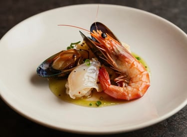 Gourmet main course featuring fresh seafood, artistically presented on a cream ceramic plate.