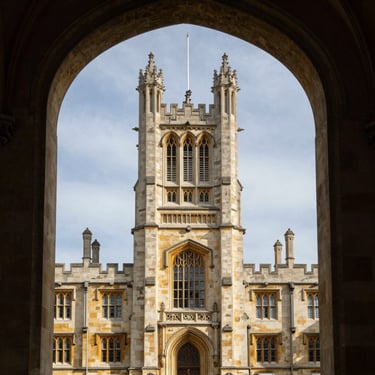 The majestic architecture of a historic UK university tower seen through a traditional stone archway, professional architectural photography.
