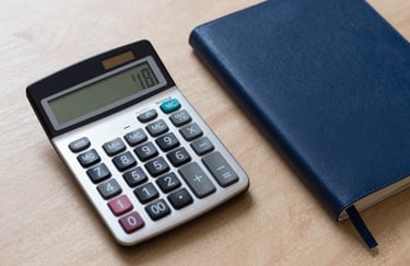 Top-down view of a tidy professional desk with a calculator and a dark blue notebook, sharp focus, professional business lighting with steel blue accents.