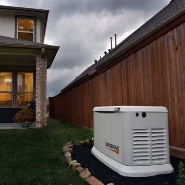 Generac standby home backup generator installed in a backyard next to a house under a stormy sky.