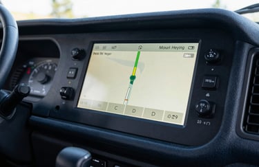An interior shot of a commercial truck cabin featuring a modern GPS dashboard glowing in Soft Off-white against Dark Navy trim.