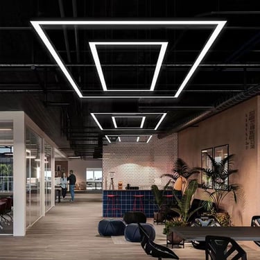 Interior de oficina moderno con luminarias LED geométricas y diseño de techo industrial.