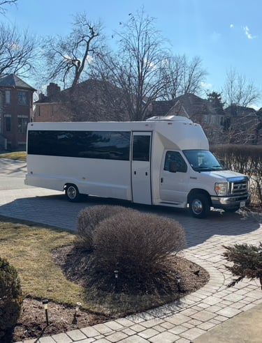 White luxury party bus parked on a paved residential driveway for group transportation services.