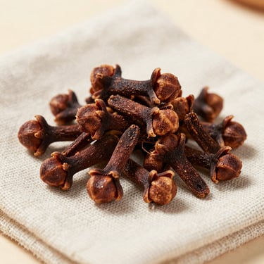 A pile of aromatic dried cloves on a textured off-white linen cloth with soft, sophisticated lighting.
