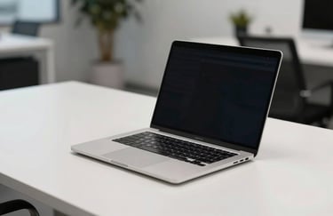 A silver grey laptop sitting on a clean white desk in a minimalist North American / US office space. The lighting is professional and even.