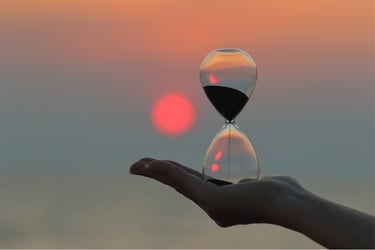 Reloj de arena sobre la palma de la mano de una mujer en el atardecer