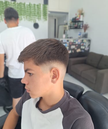 Side profile of a young man with a fresh mid skin fade haircut at a professional barbershop.