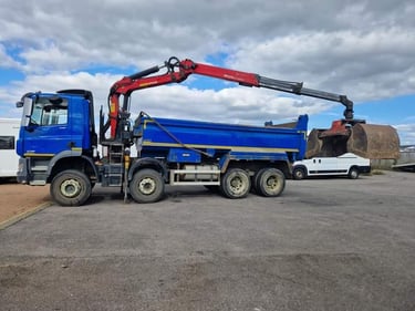 Blue grab hire tipper truck with a hydraulic red crane arm and bucket for waste removal.