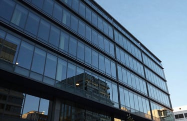 The exterior of a modern commercial office building with glass facades reflecting the South American blue sky. A clean, architectural shot that transmits stability and corporate presence.