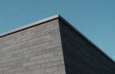 A cinematic shot of a modern roof corner with charcoal grey shingles against a crisp steel blue sky, symbolizing precision and durability.