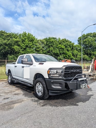 A white Ram 2500 heavy-duty pickup truck with an off-road bumper and winch parked outdoors.