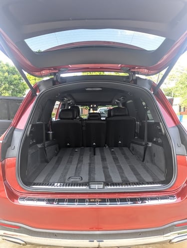 Spacious empty trunk of a modern red Mercedes SUV with folded rear seats showing cargo capacity.