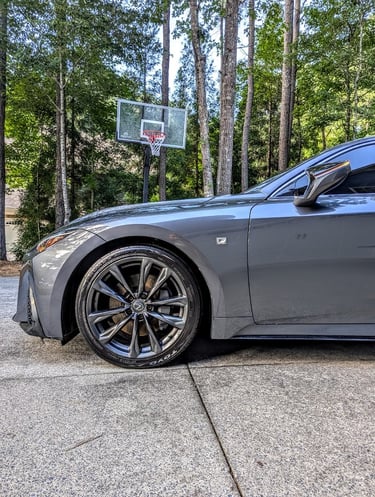 Side view of a grey Lexus IS F Sport showing the alloy wheel and Toyo tires parked in a driveway.