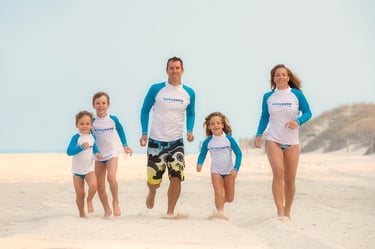 Family of five running along white sand beach under blue sky, Perth beach family photography Fisher Photography