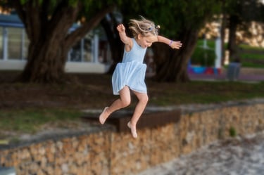 Young girl jumping with joy at Point Walter Reserve, candid children's photography Perth by Fisher Photography