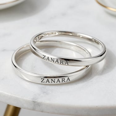 Set of silver bracelets with clean lines and a matte finish, arranged on a black velvet cloth.