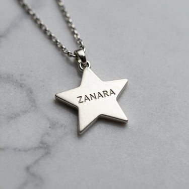 Elegant silver necklace with a minimalist design displayed on a white marble surface with soft natural light.