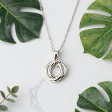 Elegant silver necklace with a minimalist design displayed on a white marble surface with soft natural light.