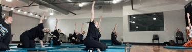 a group of people doing yoga exercises on a wooden floor