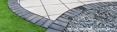 Patio with custom stone circle with aggregates and paving weaving through adventurous garden design