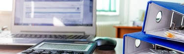 a desk with a calculator and a laptop