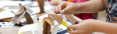 A child sticking paper strips to a concertina cardboard structure.