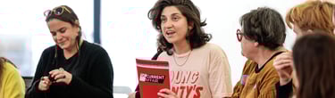 A person holding an education resource booklet up and smiling.