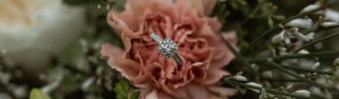 a diamond ring with a diamond ring on top of a bouquet of flowers