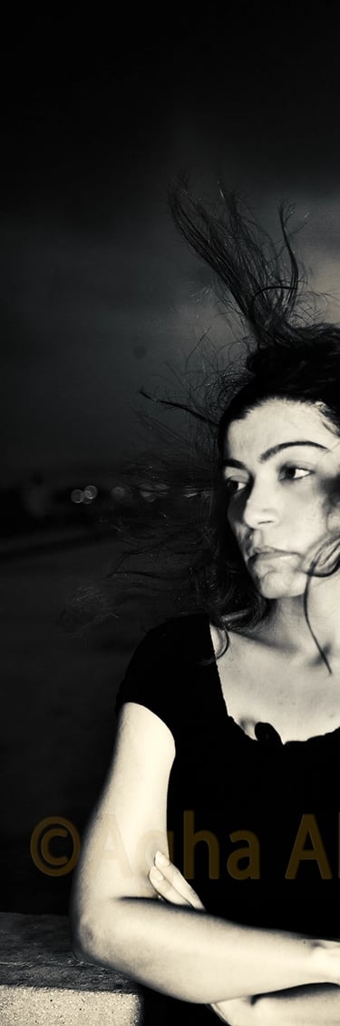 B&W photograph of a girl with the wind blowing her hair upwards. 