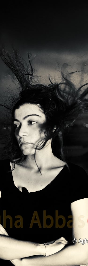 B&W photograph of a girl with the wind blowing her hair upwards. 