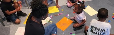a group of children sitting on the floor in a circle drawing
