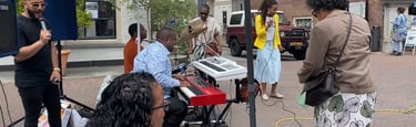 a group of people standing around a piano outside singing
