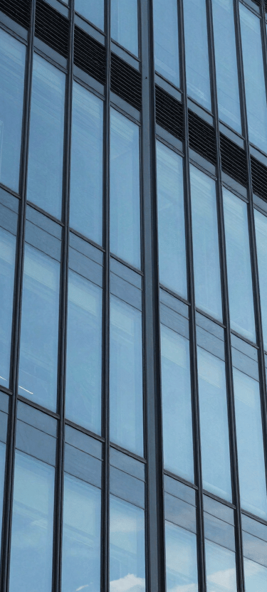 A modern North American / US office building with glass windows reflecting a clear sky blue sky. The image represents the innovative and solid foundation of our company.