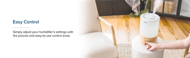 Levoit humidifier on stool with user hand adjusting control knob in sunlit living room