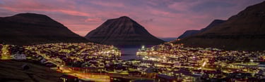 Sunset casts vibrant hues over Klaksvík, a picturesque town in the Faroe Islands, creating a serene evening atmosphere.