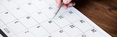 Close de profissional agendando compromisso em calendário de papel, simbolizando organização e planejamento