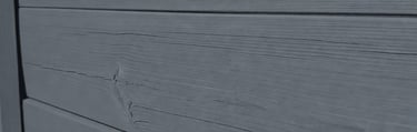 A wood fence with deep grey matte finish created with traditional linseed oil paint