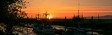 a sunset over a river with boats docked at the dock