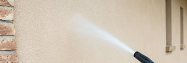 a person using a pressure gun to clean a house