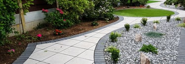 Patio with custom stone circle with aggregates and paving weaving through adventurous garden design