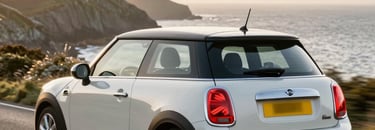 A friendly driving instructor smiling beside a car on a sunny day in Newquay.