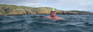 Graeme Lowe in the sea beneath cliffs