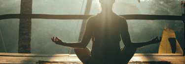 Person meditating in lotus position during sunrise at a tropical wellness retreat