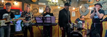 BSide blues performing classic rock music on a small stage inside a rustic bar.