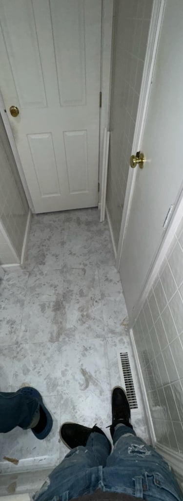 Small bathroom renovation featuring gray marbled floor tiles, white wall tiles, and a compact vanity.