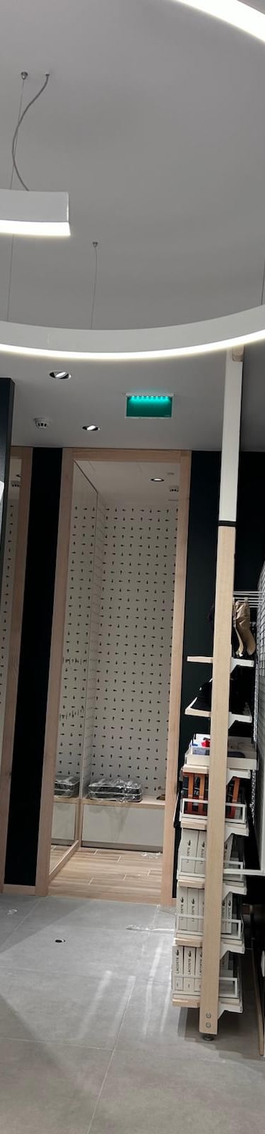 Modern retail clothing store interior with geometric wall art and circular LED lighting.