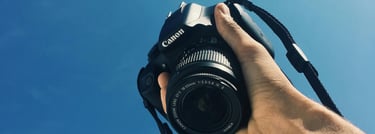 a person holding a camera and taking a picture with a bright blue sky