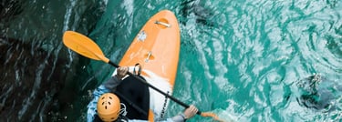 an adventurous person in a kayak in teal blue water