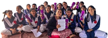 Ambassador Pooja sitting on the floor with a group of girls.. They are holding menstrual education i